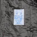 Close-up of vintage original Italian military trench coat inner label and quilted khaki lining with care instructions.