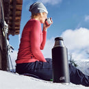 Black ESBIT SCULPTOR vacuum flask in snow with person drinking from a cup in outdoor winter setting
