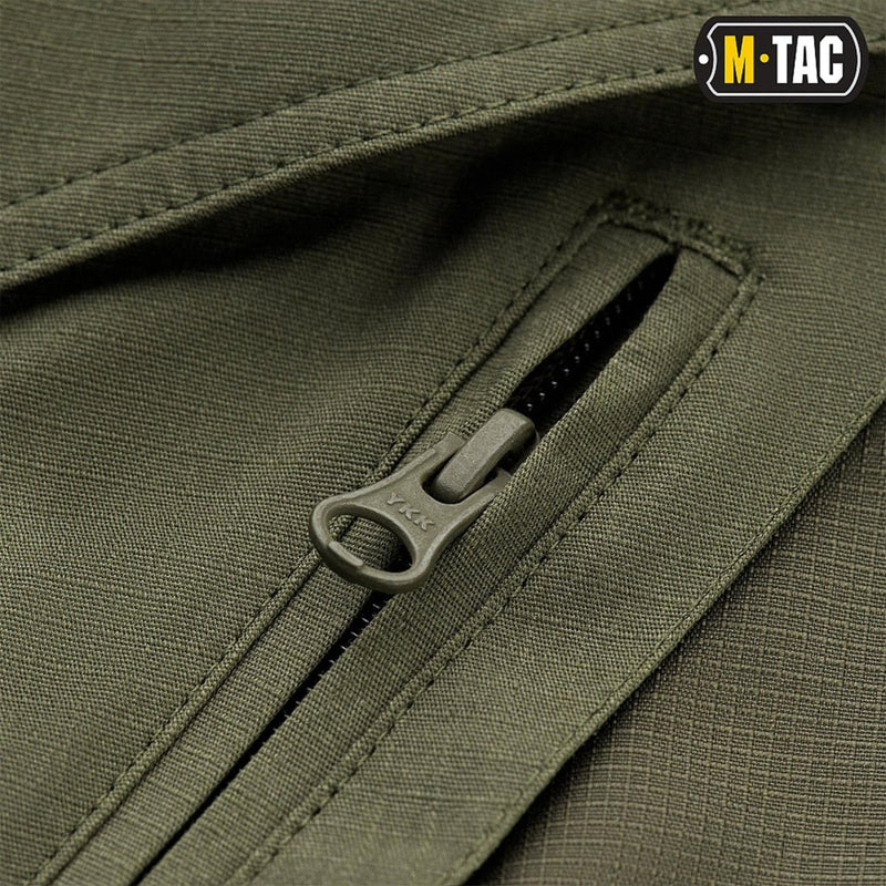 Close-up of olive green M-TAC military grade Bermuda shorts zipper with ripstop fabric texture.