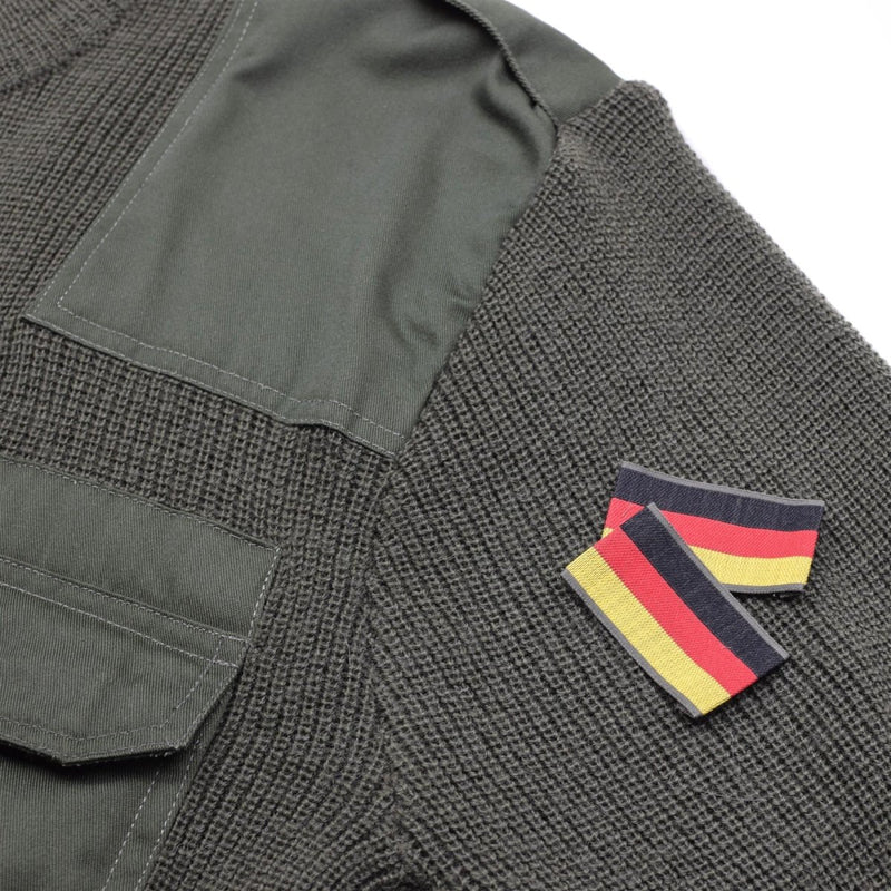 Close-up of olive green Mil-Tec German Bundeswehr wool sweater with fabric pocket and German flag patch on sleeve.