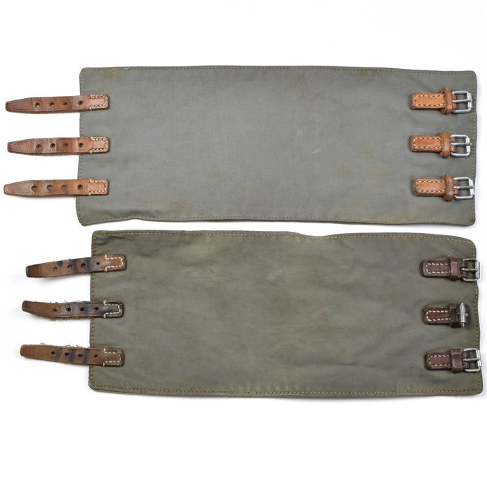 Ett par vintage Austrian Army M58 bendamasker med läderremmar och metallspännen i olivgrön militärstil