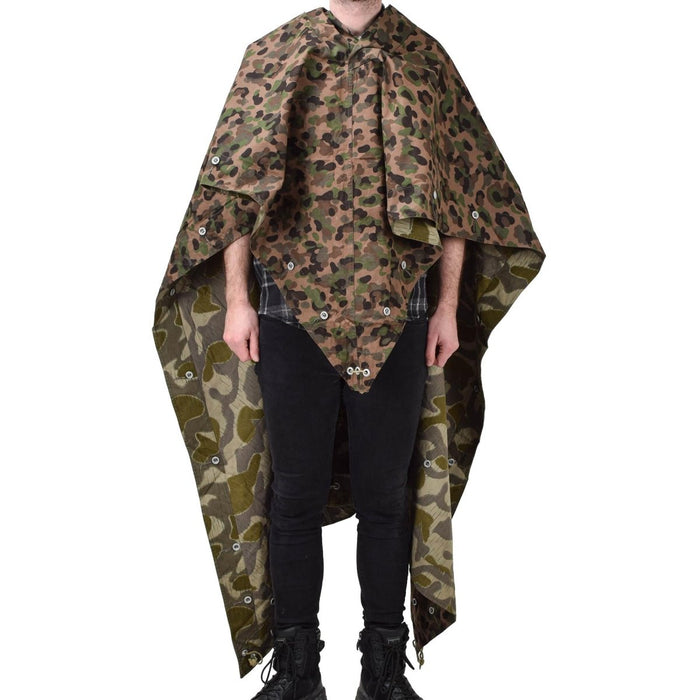 Person som bär vintage österrikisk armé vattenavvisande ärtprickar splinter camo poncho tält med hörnband