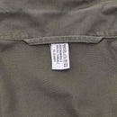 Close-up of olive green fabric with a white care label showing material and washing instructions on military jacket