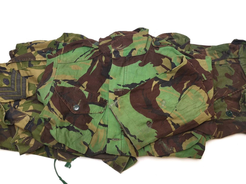 Original British army BDU combat smock in woodland camo with multiple pockets and adjustable fit for cold weather use.
