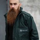 Man wearing original British Police green waterproof anorak parka with police badge patch on chest pocket