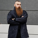 Man with long beard wearing a dark blue Dutch police issue parka jacket standing with arms crossed