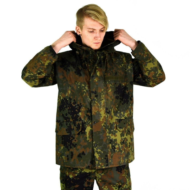 Man wearing original German army GoreTex flecktarn waterproof camouflage rain jacket with hood up