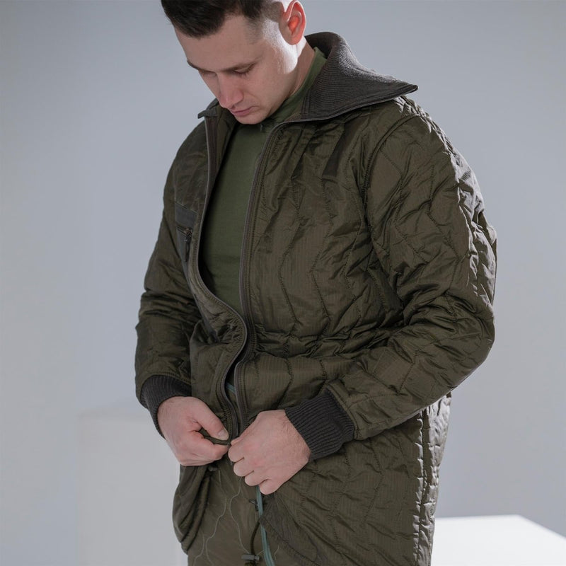 Man wearing a quilted olive green German army field jacket parka with knit collar and cuffs fastening zipper