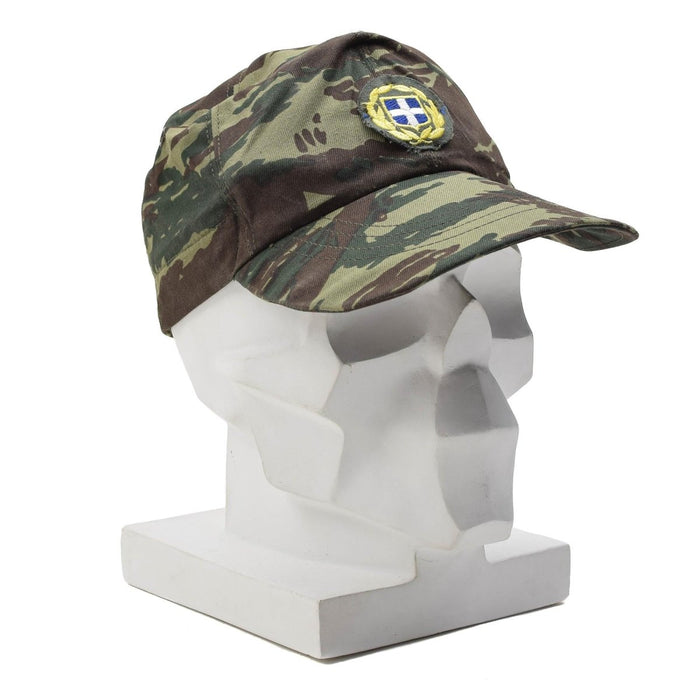 Grekisk militär överskottsödla camo fältkeps med grekiskt emblem, hållbar och designad för utomhusbruk.