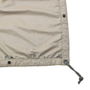 Close-up of beige reversible military tarp ground cover with reinforced edges, grommets, and corner cord for securing.
