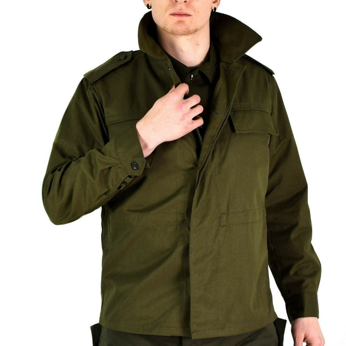 Man bär en original vintage tjeckisk M85 olivgrön militär fältjacka med knäppta manschetter och epauletter