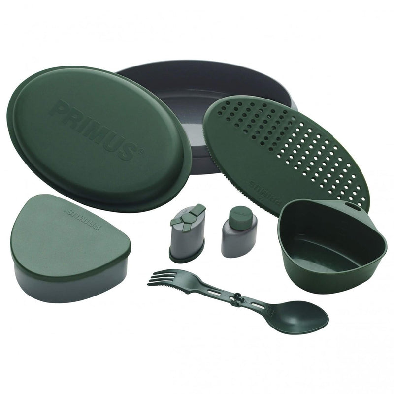 Compact green Primus Frigg W Piezo camping mess kit with plates, cup, utensils, and spice containers for outdoor meals.