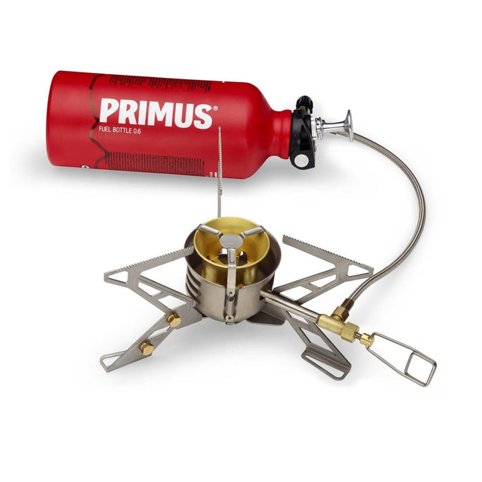Primus OmniFuel II flerbränslecampingkamin med röd bränsleflaska och hopfällbar stativbrännare för matlagning utomhus.